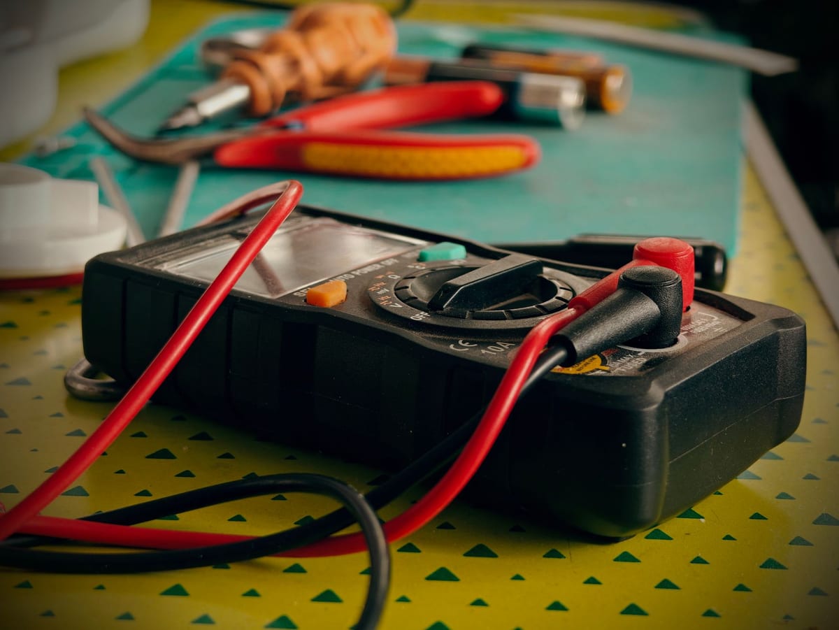 Multimeter and hand tools laid out on a workbench